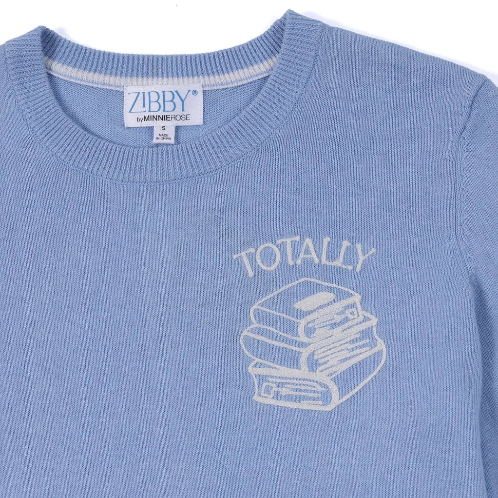 Light blue sweater with 'TOTALLY' and book illustration, brand label visible.