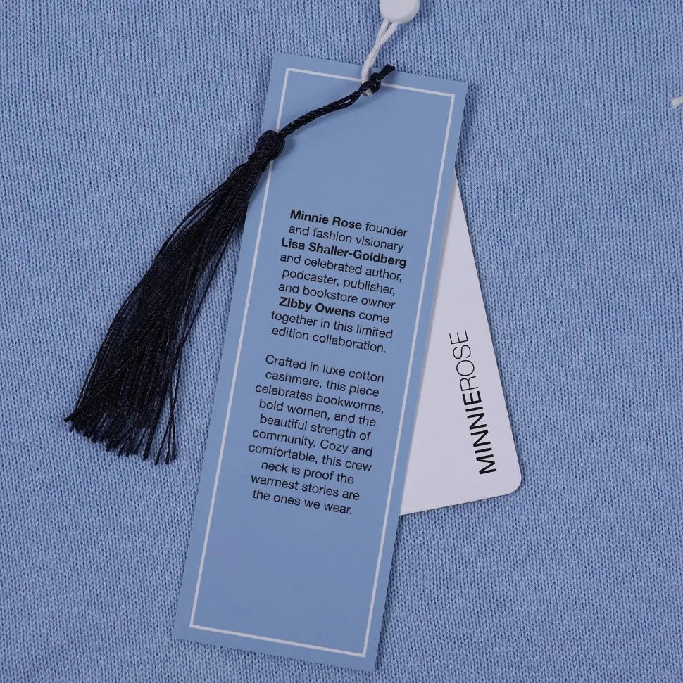 Blue sweater with a Minnie Rose tag and tassel on a blue background